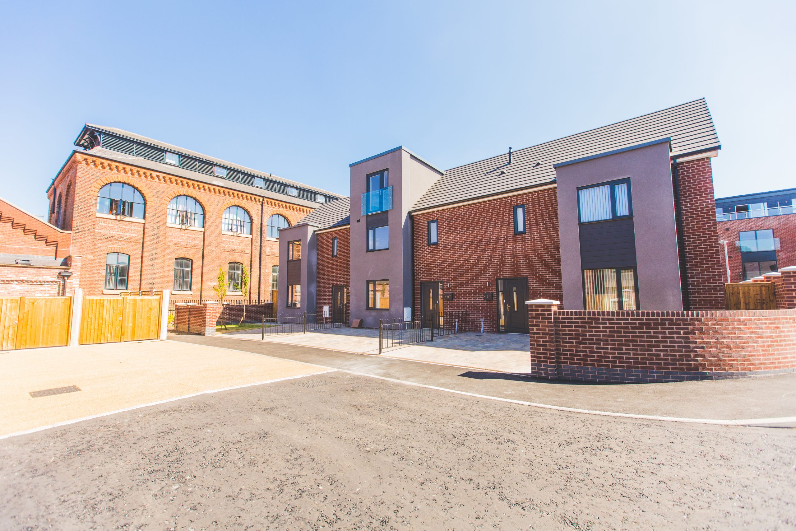 Large open area with two red brick building, one with arched window and the other with square windows.