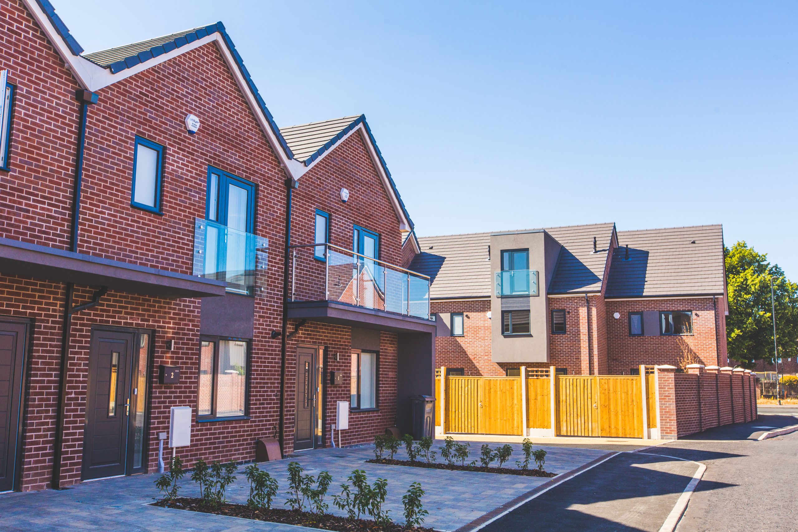 Close up view of two terraced houses with light block drives with a wooden fence and further terraced houses in the distance.