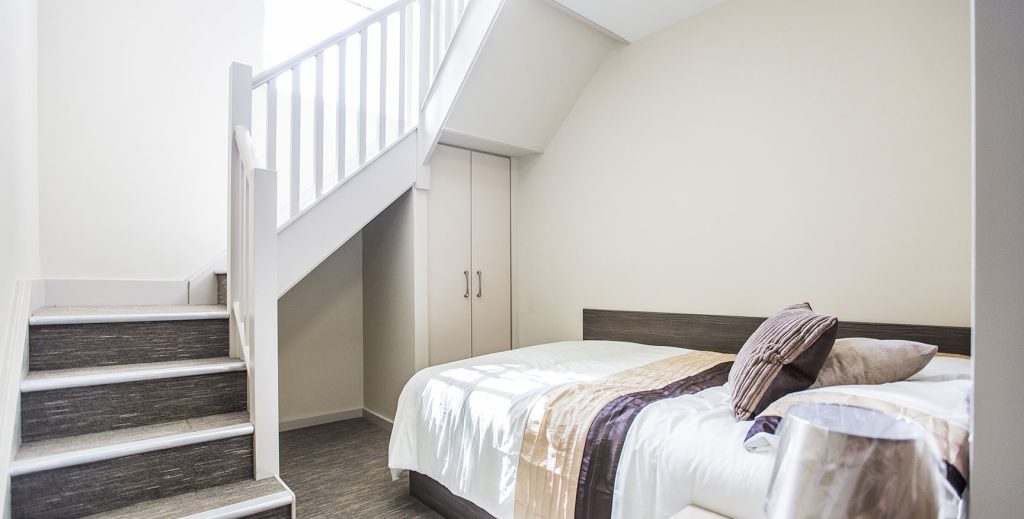 View of bed with stairs going up and over bed.
