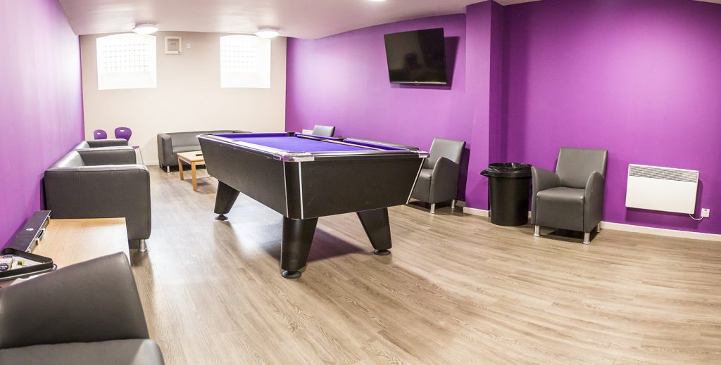 Games room with purple walls, wooden floor and leather sofas and chairs