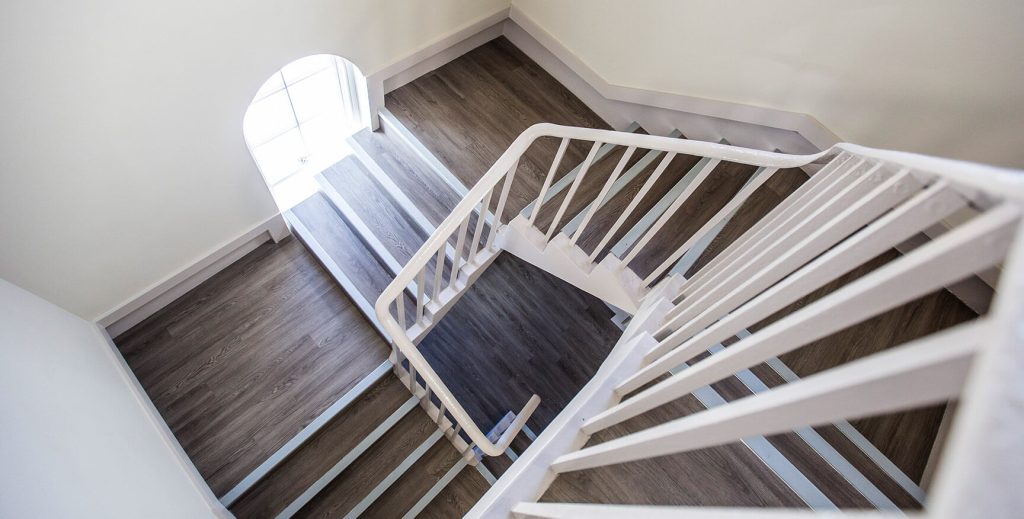 View of stairs twisting down with wooden floor.