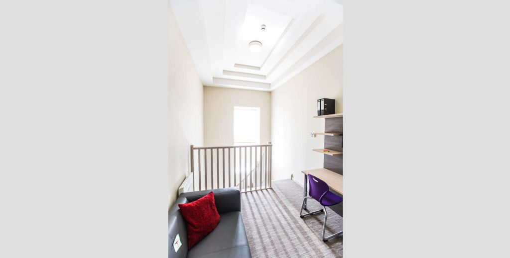 Open area in student room showing wooden desk and bright window in the background.