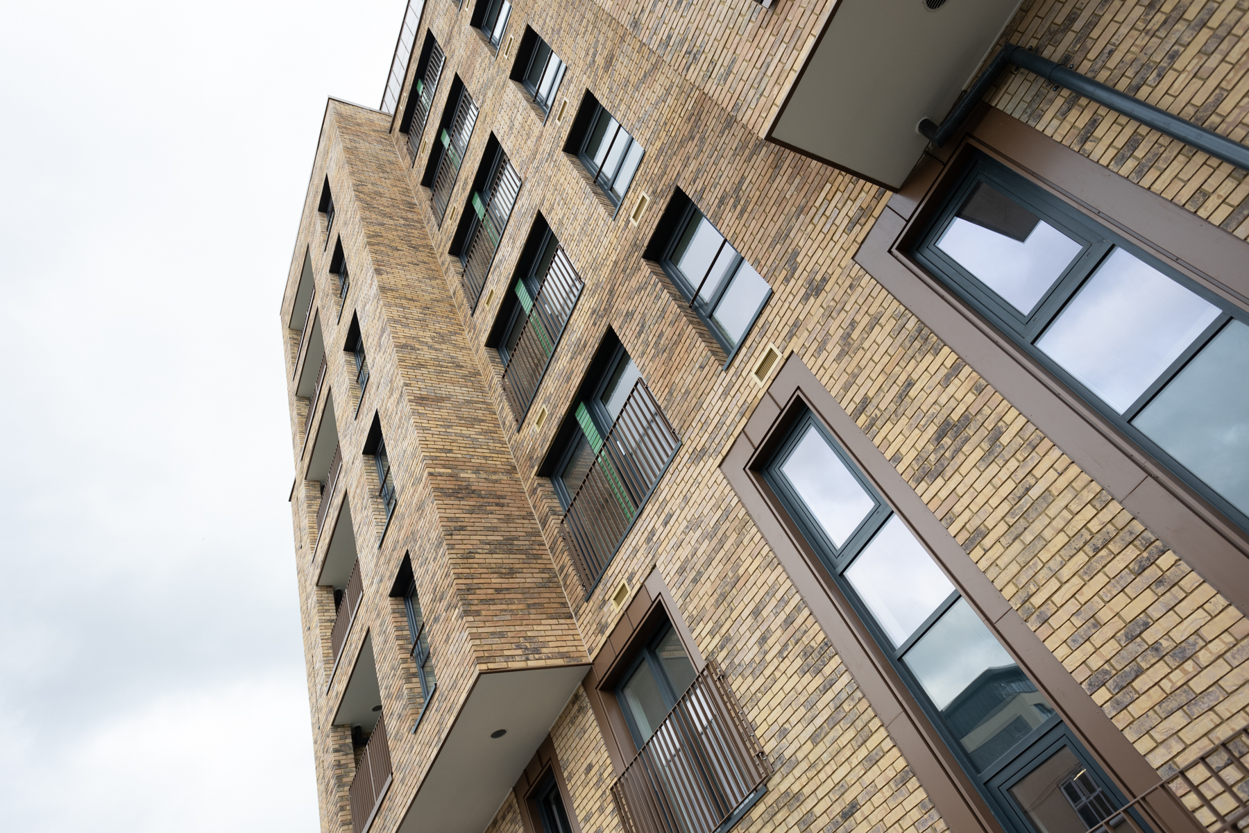 Exterior view looking up at The Waterhouse with its light brown and grey brickwork and tall rectangular windows.
