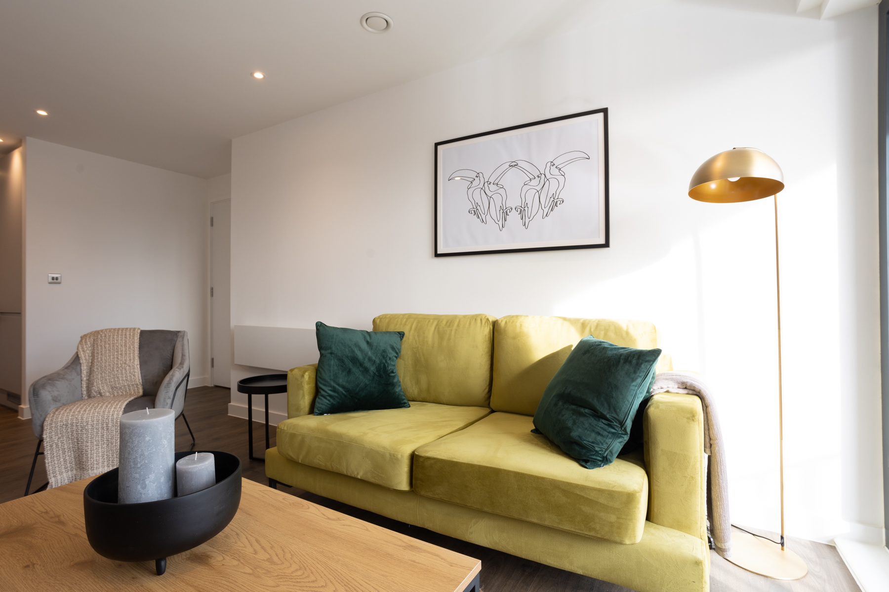 Interior view of lounge with light green double sofa, white walls and wooden coffee table.