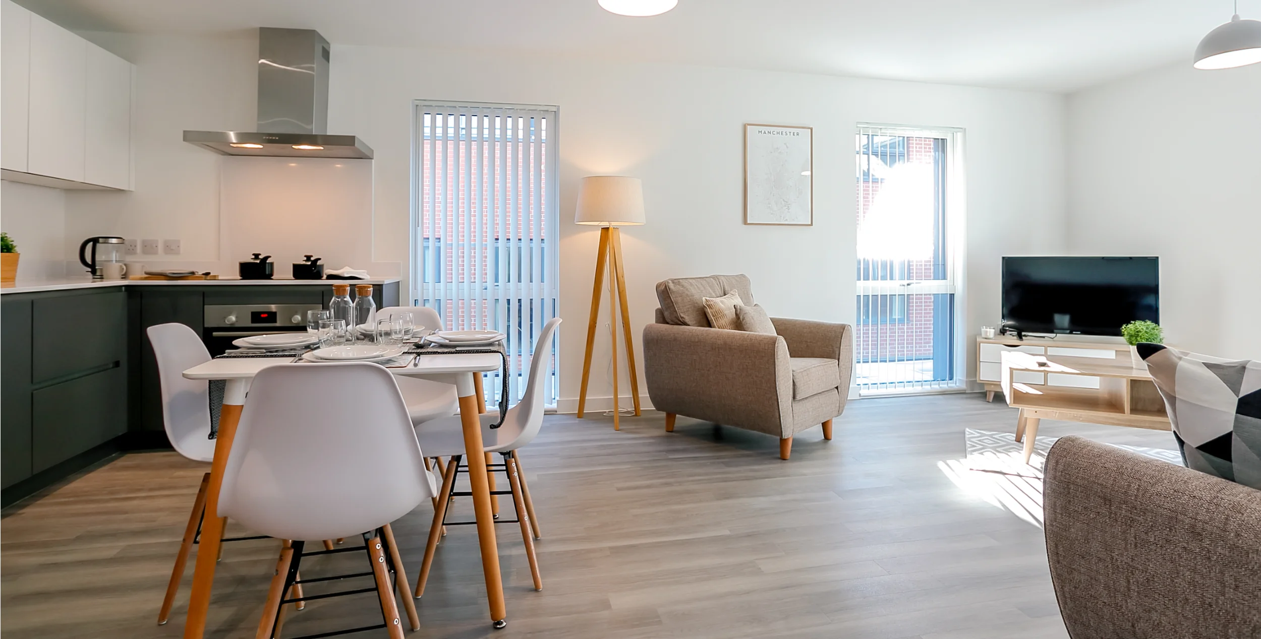 Large open plan kitchen diner with dark grey kitchen units, dining table, armchair and TV.