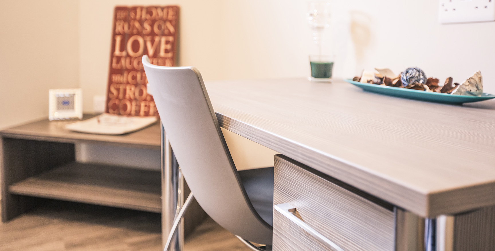 Grey study table and chair with a low coffee table in the corner of the room.