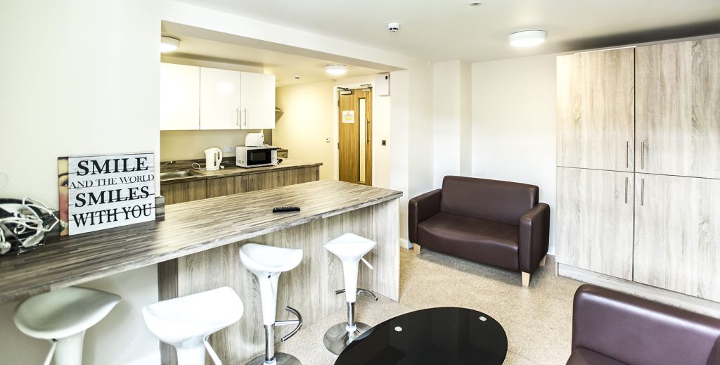 View of an open kitchen diner with peninsular unit and a leather sofa in the back ground.