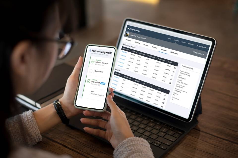 Woman using PRIMO RESIDENTIALS Landlord PropertyFile on a mobile phone and a tablet.