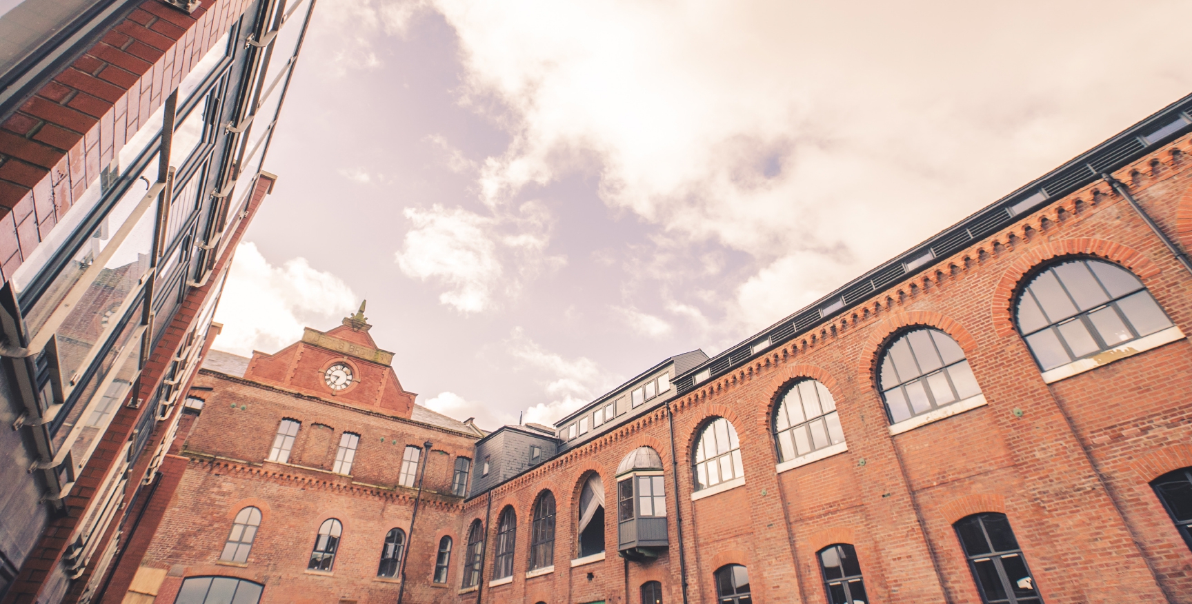 Looking up at the brick structure of Queens Brewery and sky from Court yard