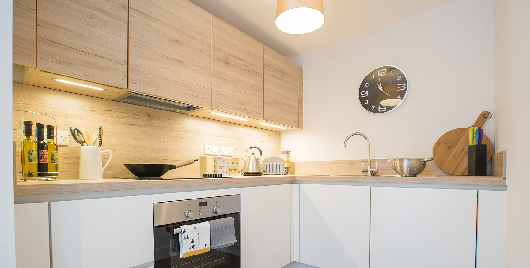 White bright kitchen with light wooden wall units above.