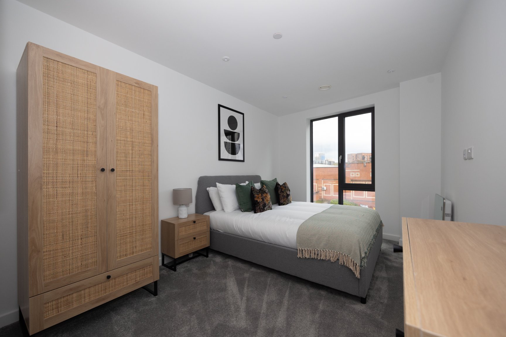 Silkbank Wharf bedroom with large bed, grey carpet and wooden wardrobe.