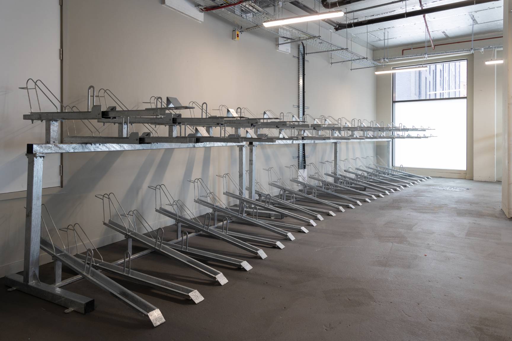 Open bright room showing a line of cycle storage racks.