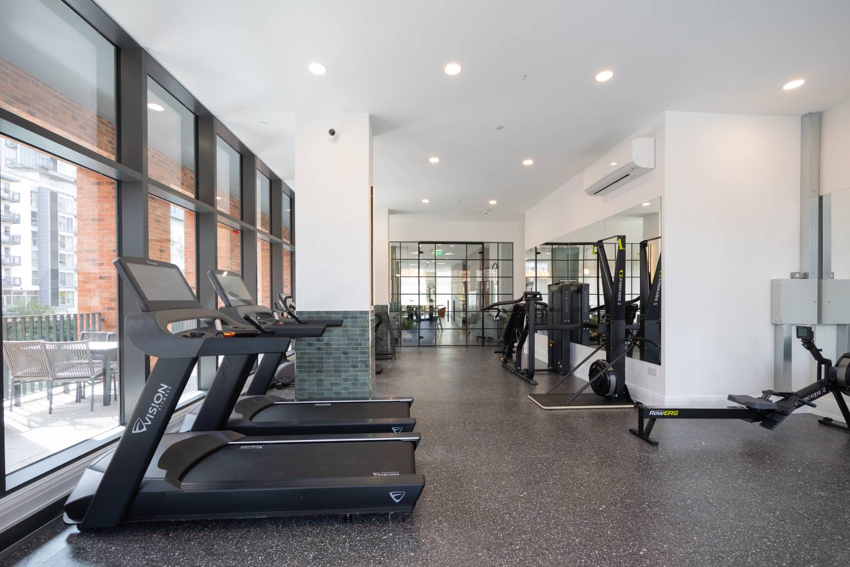 View of gym showing full length of room with rowing and running machines.