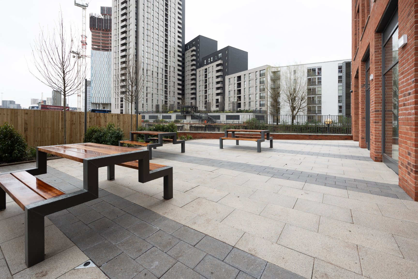 Communal exterior space to the side of the building with picnic benches and surrounding plants