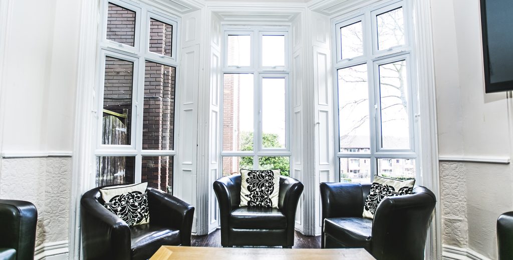 Close up view of the three large windows with three leather arm chairs in font.