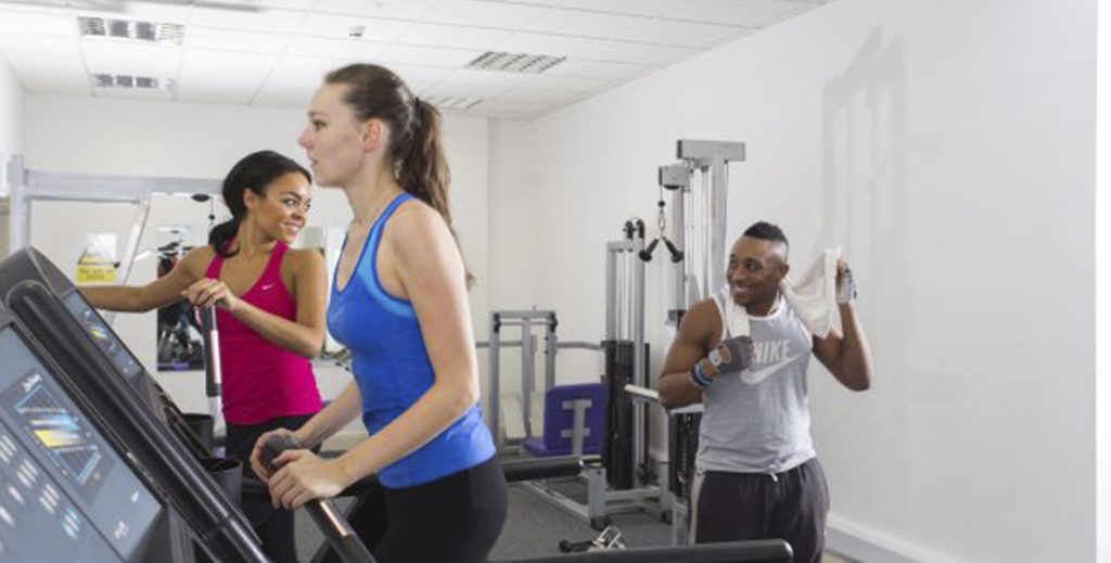 Three students in the gym using the equipment.
