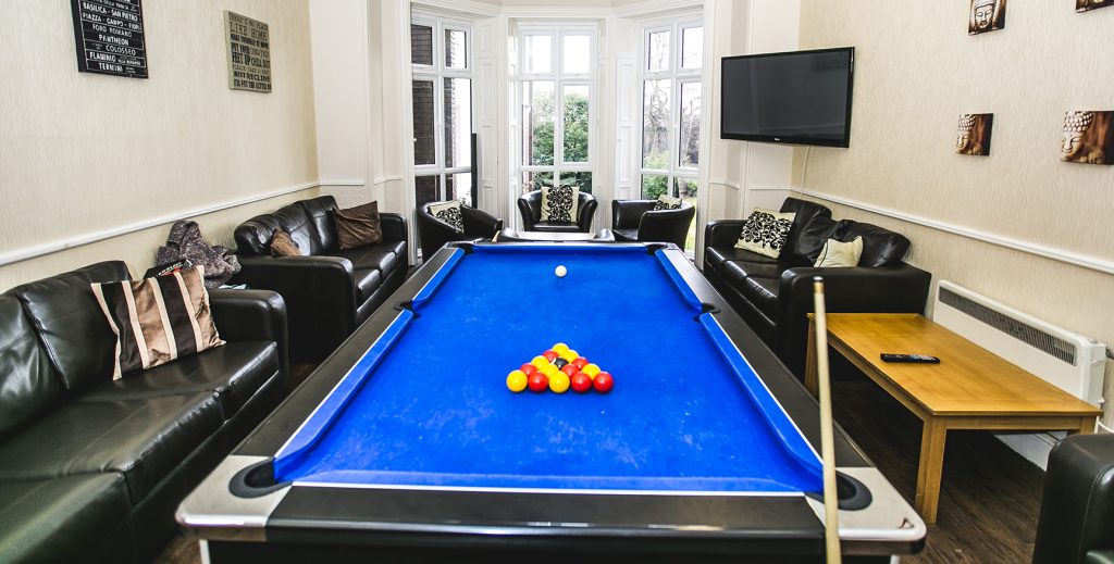 Games room with a blue pool table surrounded by leather sofas.