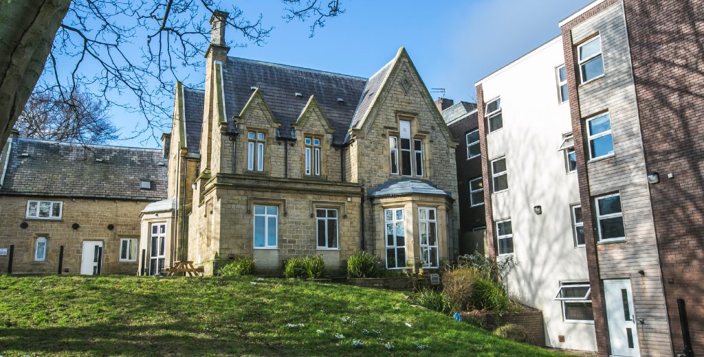Exterior view of St. Ann's Lodge, looking across an open grassed area with both a modern and period building attached
