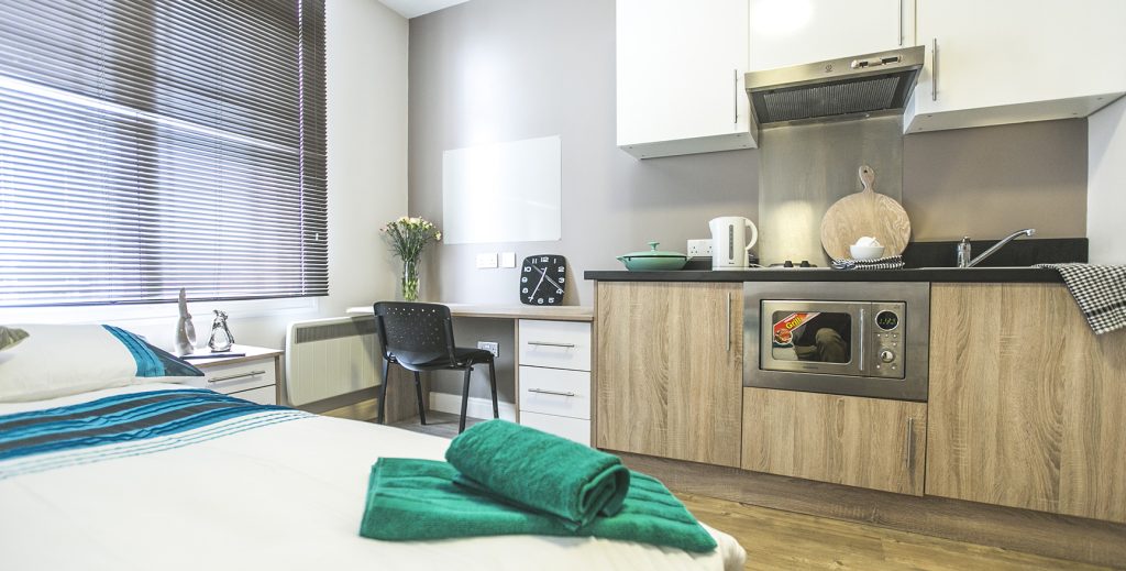 Forty five degree angle of bed desk and kitchen in the room