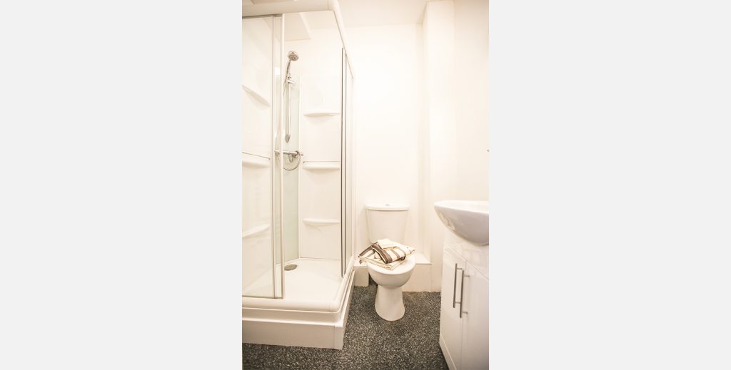 Bathroom with dark tiles and white shower sink and toilet