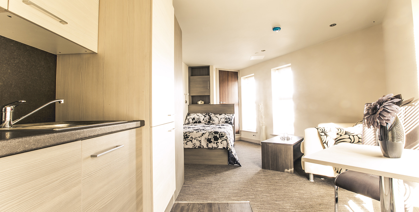 Close up view of kitchen with sofa and bed in the distance