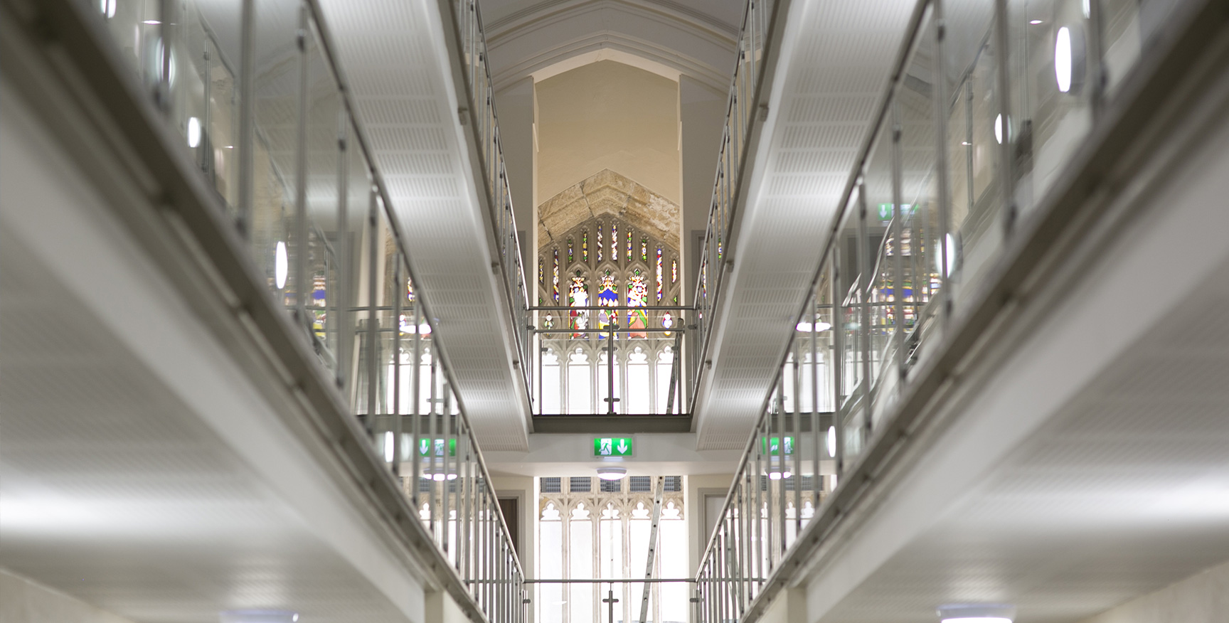 Open interior walkway with glass balustrades with stained glass window in the background/