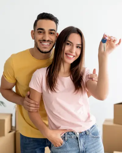 Happy tenant couple holding a door key.