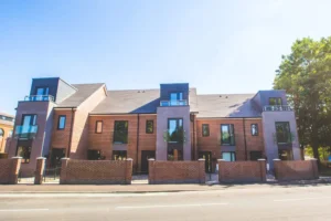 Street view of five Anvil Place terraced homes with brick frontage and three square grey extensions at the front with glass balustradess