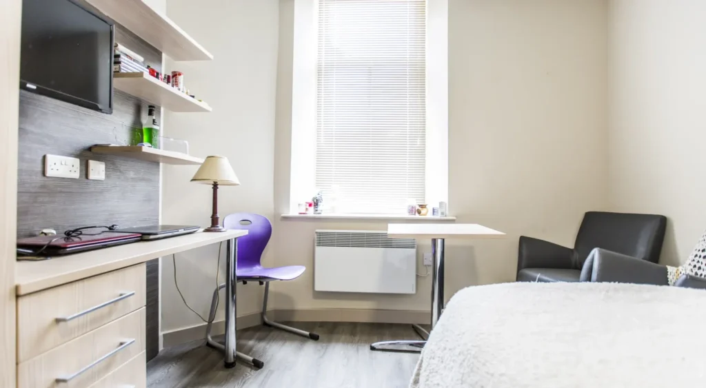Purple chair with small table, study area and TV.